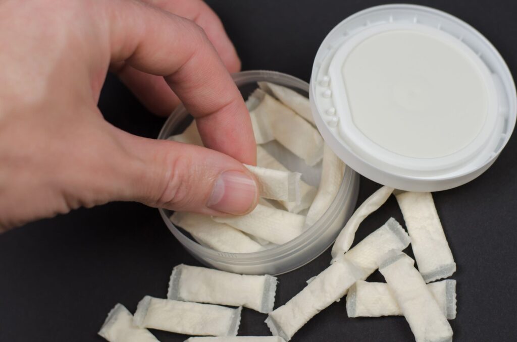 Man s hand takes a bag of swedish snus on a black 2026 01 06 09 34 04 utc